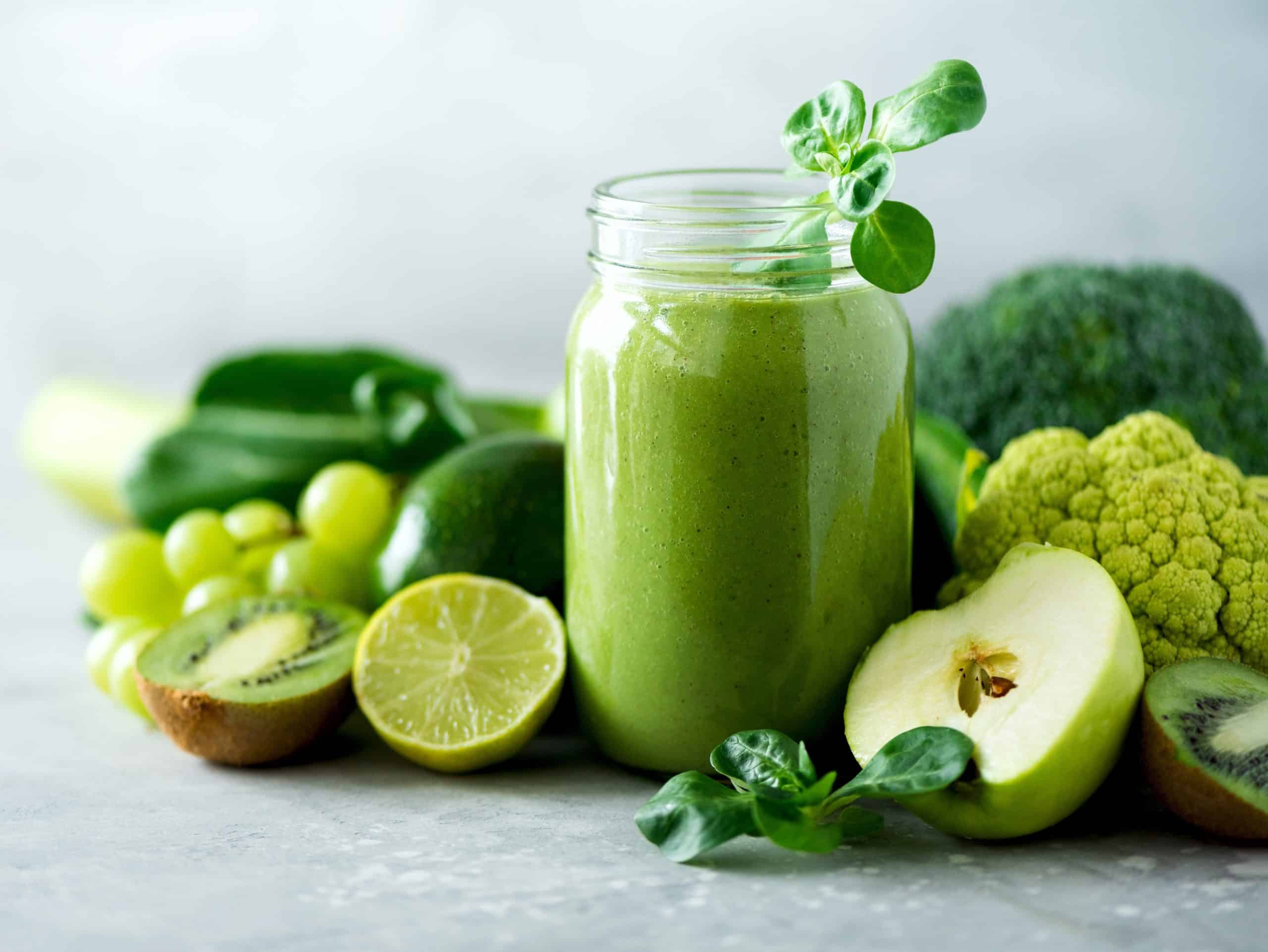 Glass jar mugs with green health smoothie, kale leaves, lime, apple, kiwi, grapes, banana, avocado, lettuce. Copy space. Raw, vegan, vegetarian, alkaline food concept. Banner